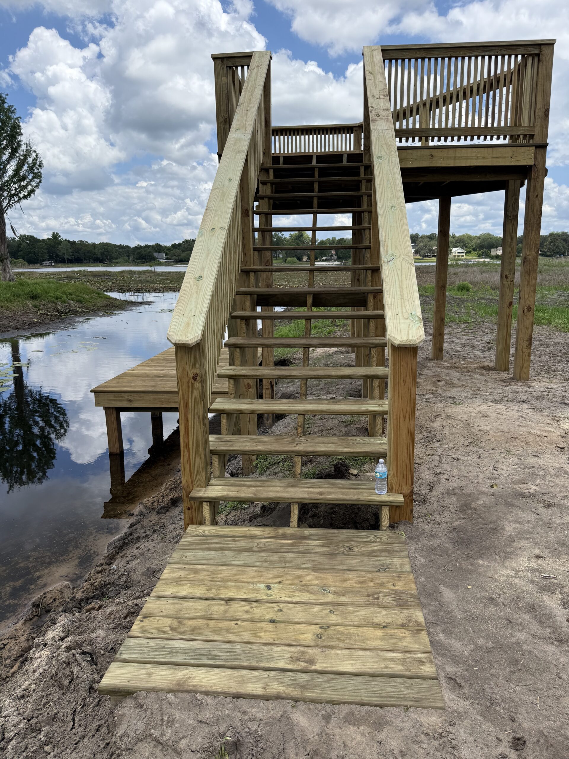 IMG_2576 - JSC Contracting Inc Wooden staircase and deck leading to a lakeside viewpoint, with water and blue sky in the background.